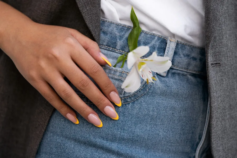 Five nails with pastel French tips in mint, baby blue, lavender, peach, and yellow on nude base.